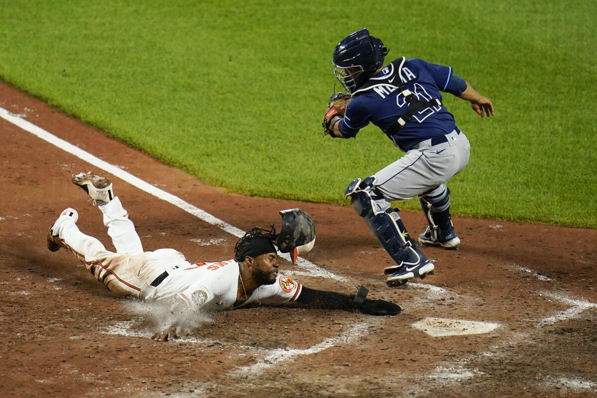 Cedric Mullins de los Orioles de Baltimore se lanza a home ante el cátcher de los Rays de Tampa Bay 