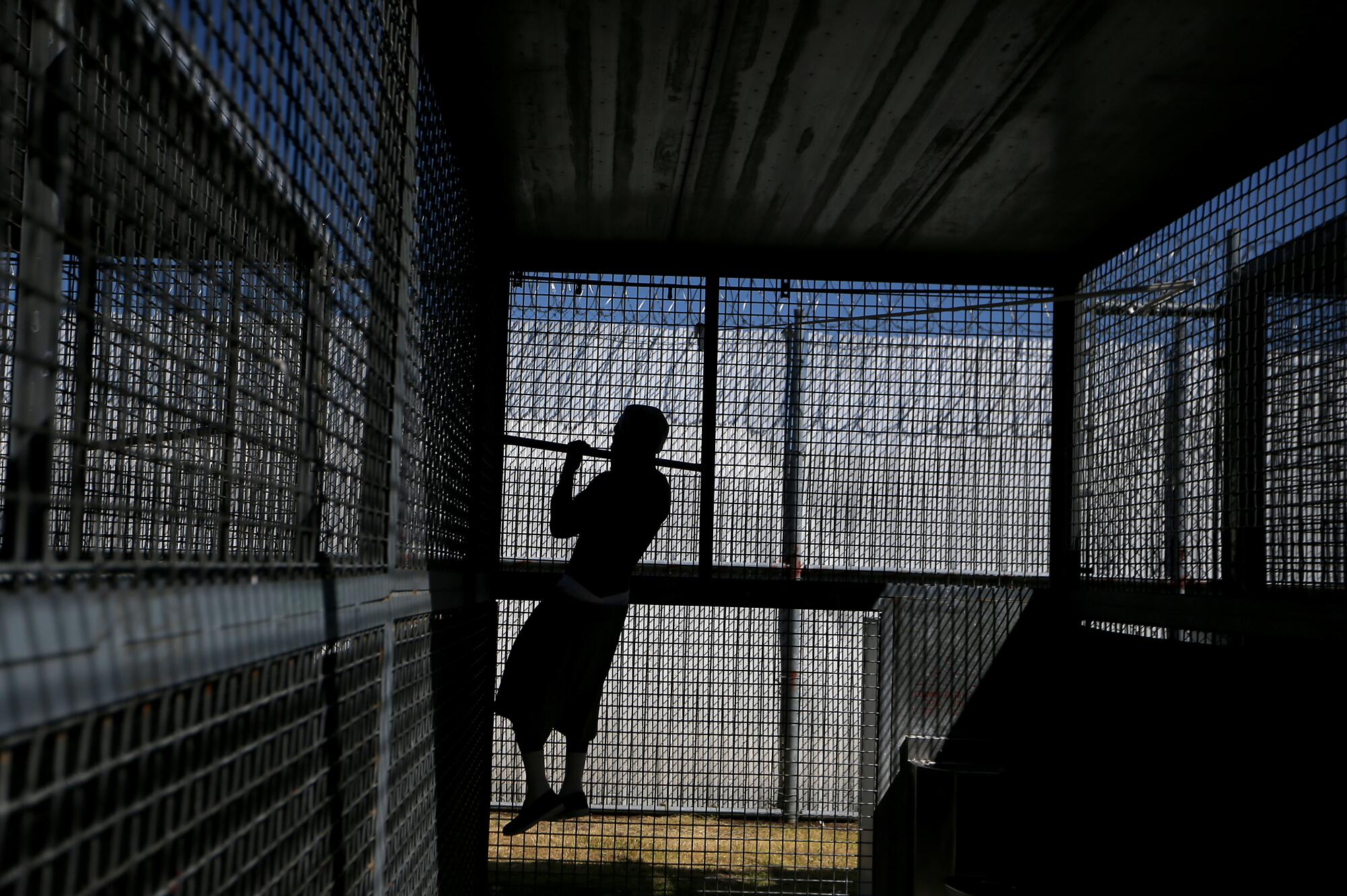 A man is confined in an outdoor cage in the exercise yard of a California State Prison.