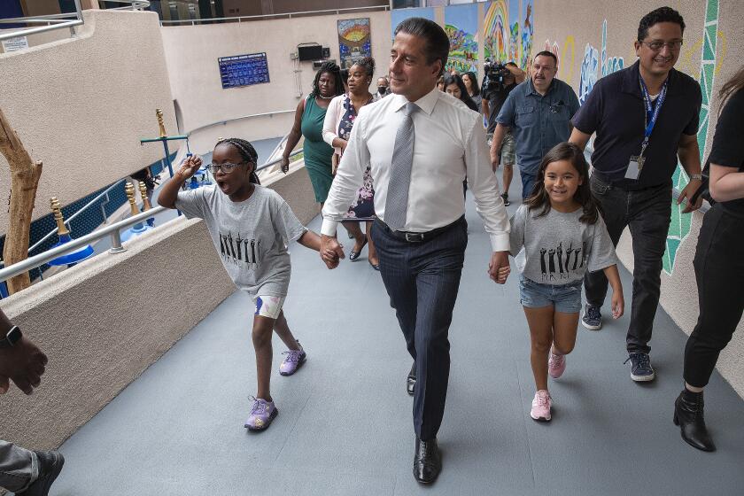 LOS ANGELES, CA-AUGUST 15, 2022: Seven Chandler, 9,left, a 4th grader at Marlton School in Los Angeles, and Kristalyn Barrera, 8, a 2nd grader, serve as ambassadors while leading Los Angeles Unified Superintendent Alberto Carvalho to a classroom during a visit to the school on the first day of class. (Mel Melcon/Los Angeles Times)