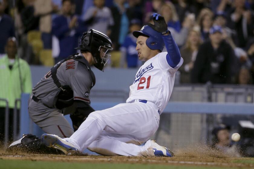 Outfielder Trayce Thompson (21) slides past Diamondbacks catcher Chris Herrmann on to score the Dodgers' first run of the game in the seventh inning.