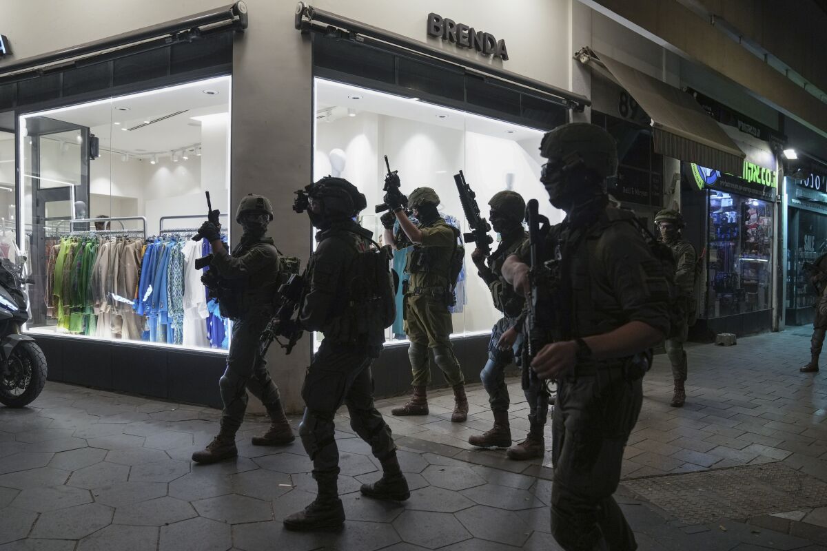 Israeli soldiers silhouetted against illuminated shop window