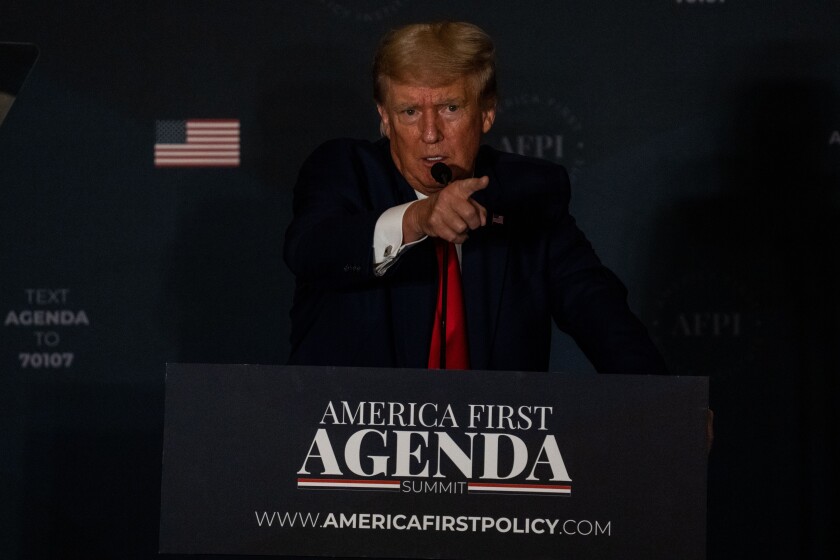 Donald Trump stands at a lectern and points his finger.