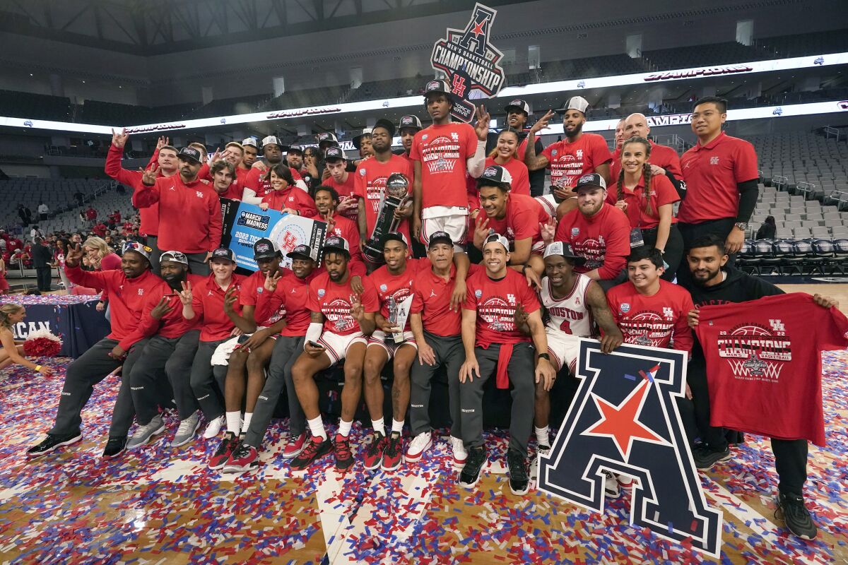 Houston players and staff pose for photos after defeating Memphis in an NCAA college basketball game for the American Athletic Conference tournament championship in Fort Worth, Texas, Sunday, March 13, 2022. (AP Photo/LM Otero)