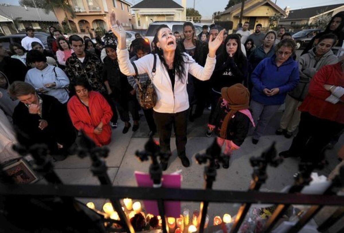 Maria Bautista leads a prayer during a vigil in front of the Wilmington home where the Lupoe family was found dead Tuesday. More photos >>>