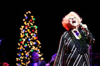 Brenda Lee sings onstage in front of a Christmas tree.