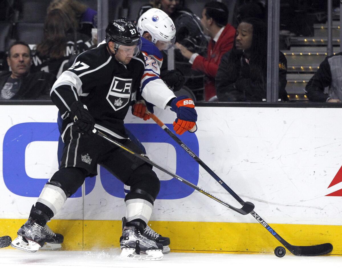 Kings defenseman Alec Martinez, left, pinches Oilers forward Adam Cracknell, right, against the boards during the third period of a game on March 26.