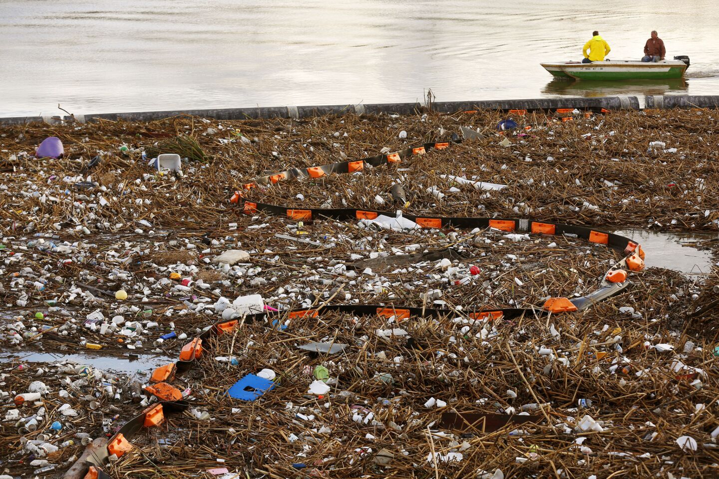 Trash floats up against a boom near the mouth of the Los Angles River on Thursday after two days of heavy rain.