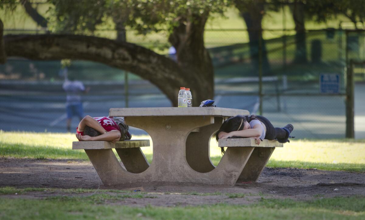 Two people nap on a picnic bench as temperatures reached close to 90 degrees Tuesday in Griffith Park