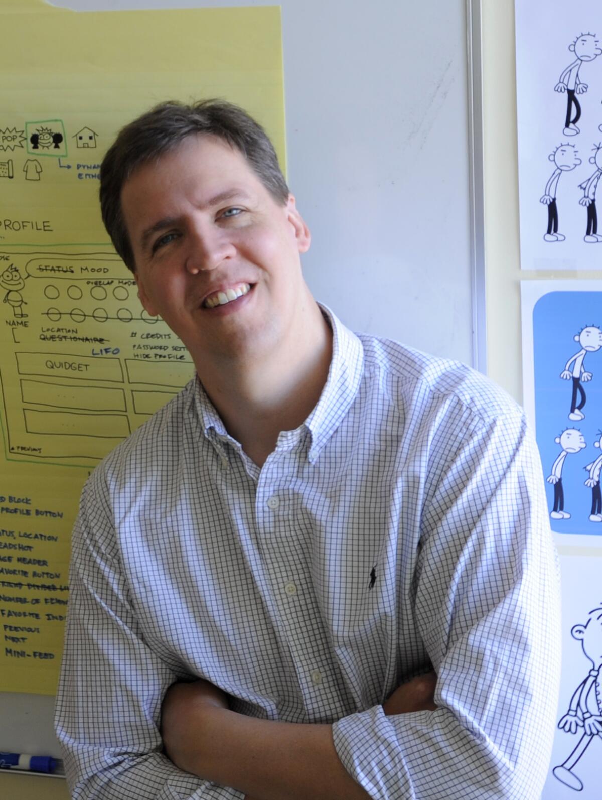 Jeff Kinney leans against a wall in his office.