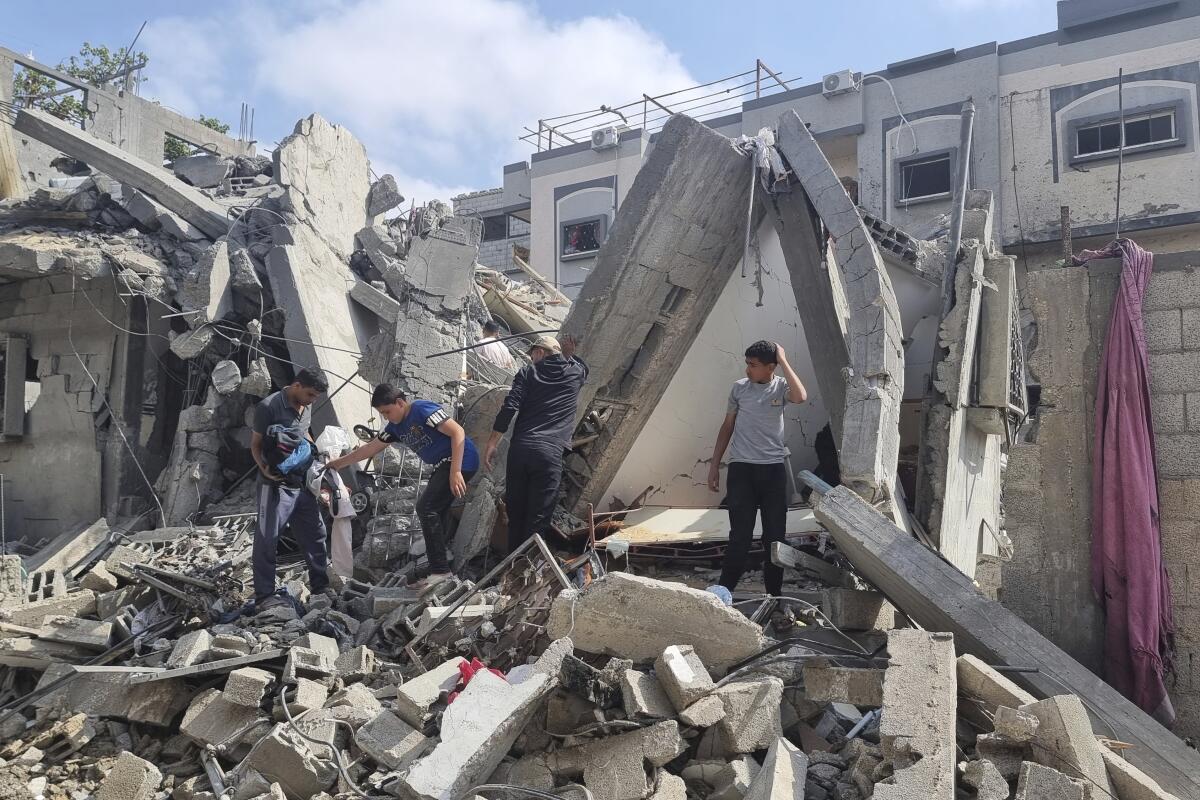 Palestinos buscan entre los escombros de una vivienda tras un ataque aéreo israelí en Rafah, en la