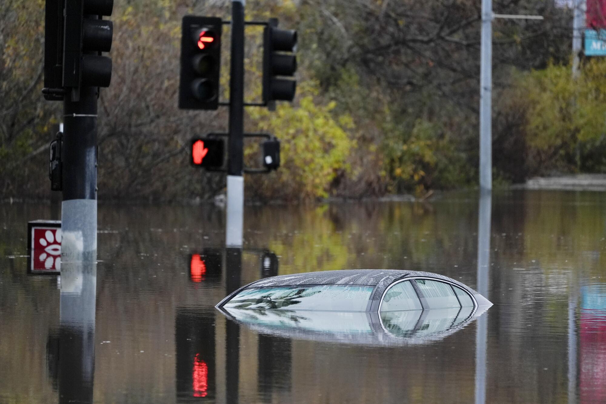 A nearly submerged car in a flooded intersection. 