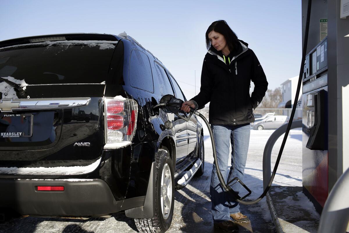 A motorist pumps fuel at the Sunoco station in Flint, Mich., on Jan. 6. Falling energy prices caused consumer spending to drop in January.