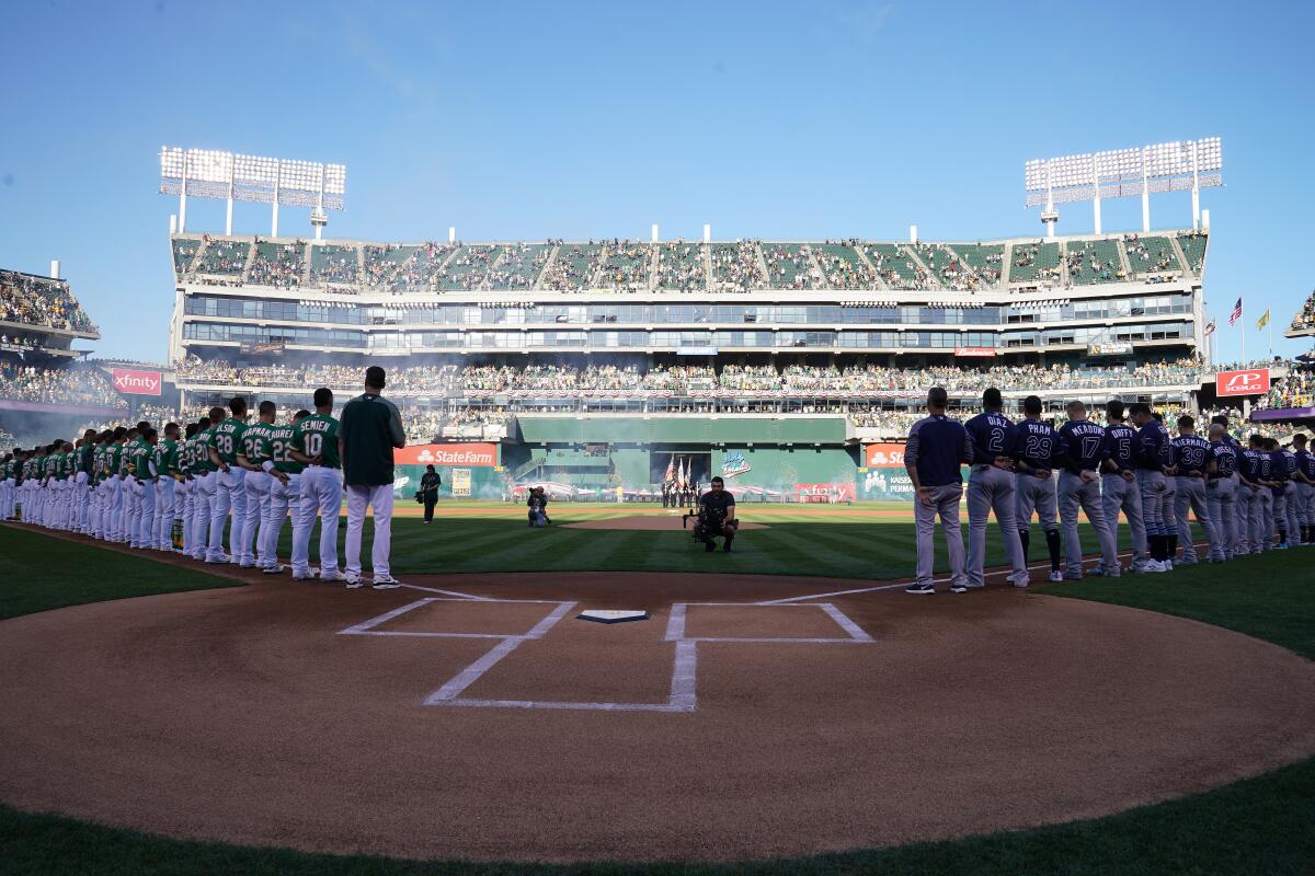 The Oakland Athletics and the Tampa Bay Rays stand during the national anthem before the American League wild-card game Oct. 2 at RingCentral Coliseum.