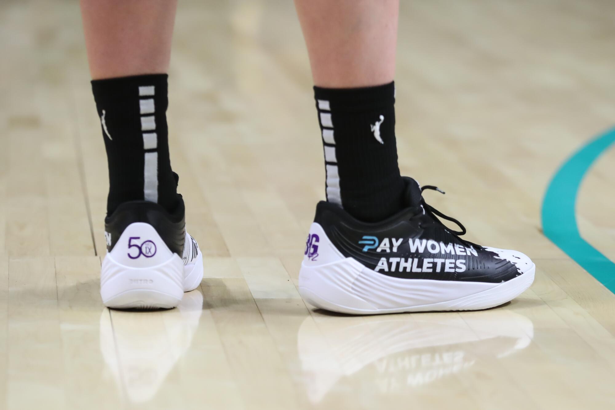 A look at the basketball shoes of Sparks forward Katie Lou Samuelson with "Pay Women Athletes" in writing.