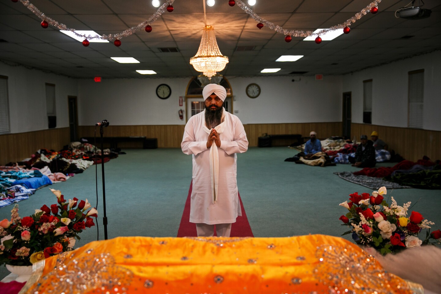 Nirmal Singh, a Sikh priest, conducts a morning prayer ritual as evacuees sleep in the background at Shri Guru Ravidass, a Sikh temple in Rio Linda, Calif., that opened its doors amid the Oroville Dam crisis.