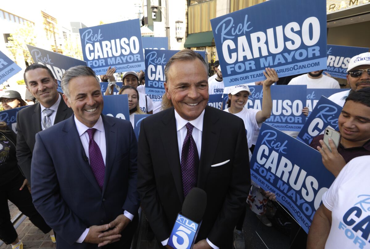 Los Angeles City Councilman Joe Buscaino and businessman Rick Caruso are surrounded by supporters.