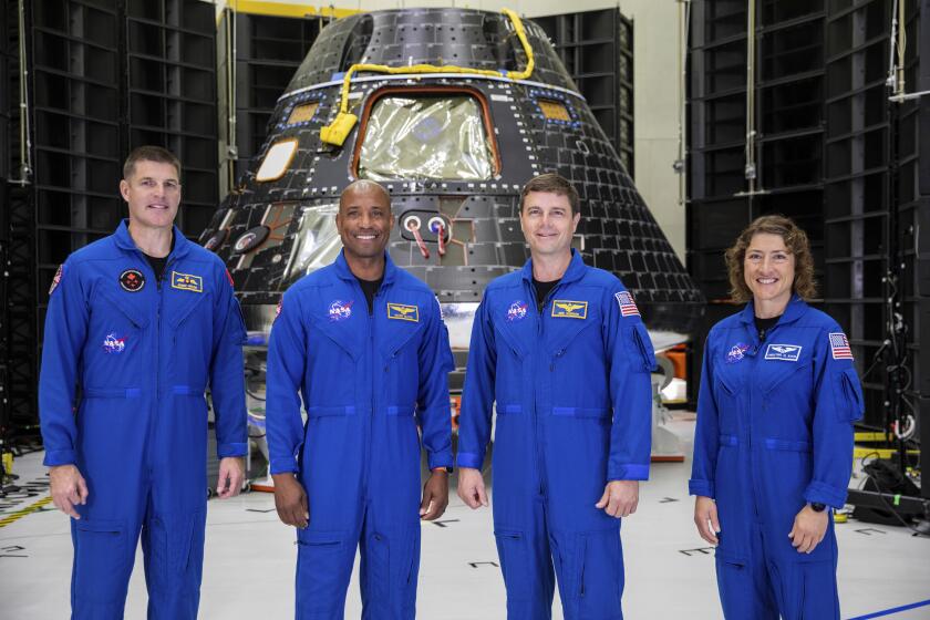 Artemis II crew members, from left, Jeremy Hansen, Victor Glover, Reid Wiseman and Christina Koch, stand together at NASA's Kennedy Space Center in Florida, in front of an Orion crew module on Tuesday, Aug. 8, 2023. The U.S.-Canadian crew inspected the capsule during a visit late Monday and Tuesday. NASA plans to send the four around the moon and back late next year. (Kim Shiflett/NASA via AP)