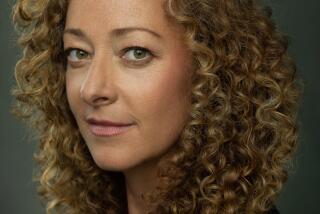 An author in profile with very curly dark blonde hair wearing black against a gray background.