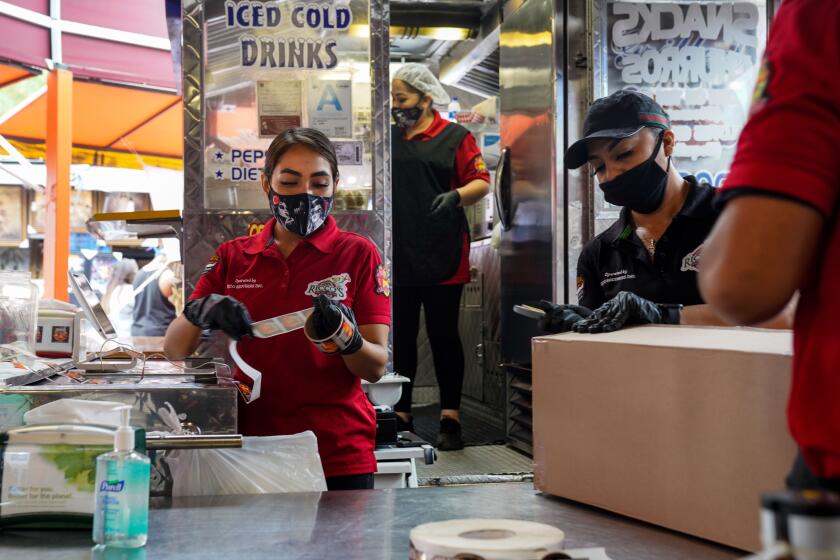 SANTA FE SPRINGS, CA - JUNE 20: Mask wearing employees work at a food booth at the Santa Fe Springs Swap Meet on Saturday, June 20, 2020 in Santa Fe Springs, CA. Swap Meets across the Southland are struggling to bounce back after finally re-opening amid the ongoing Coronavirus pandemic. (Kent Nishimura / Los Angeles Times)