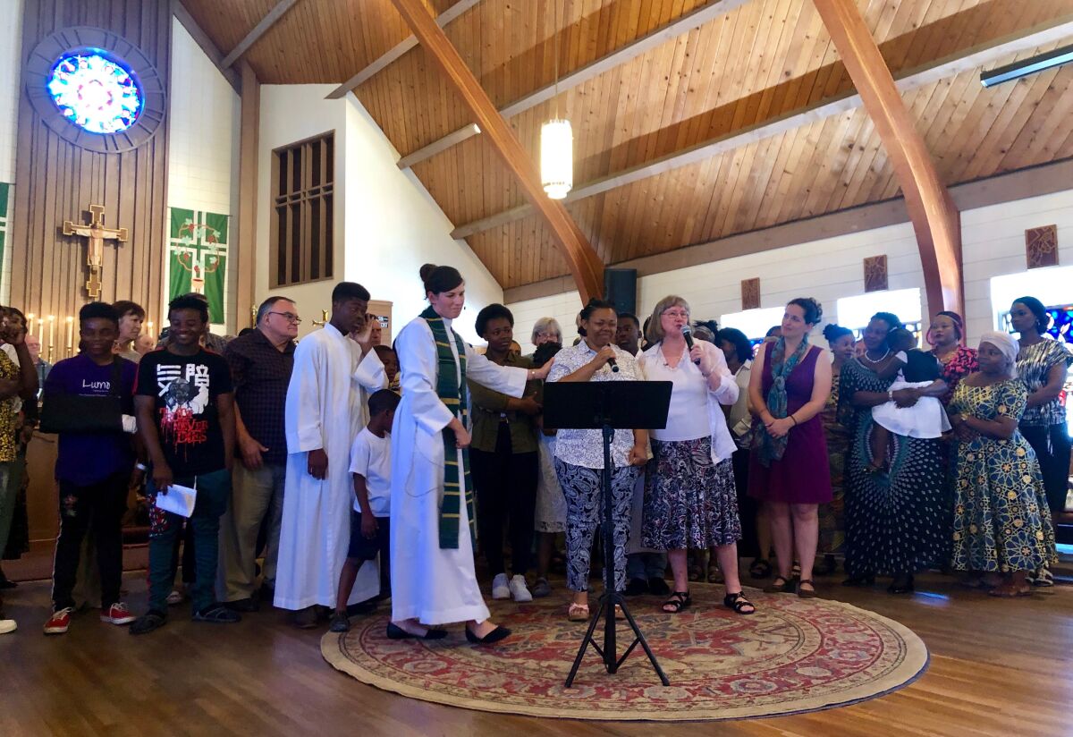 Annie Bwetu Kapongo (centro), esposa de Constantin Bakala, recibe el apoyo de miembros de la iglesia St. Luke’s Episcopal durante el servicio de este domingo 14 de julio en North Park.