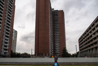 A man carries his bags near high-rises on a cloudy day