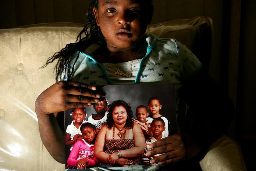 Johnetta Harrison, the sister of Dae'von Bailey, holds a portrait of Tylette Davis and her children. Johnetta is at the back on the left. Dae'von, who was beaten to death last July, leans on his mother's shoulder at right.