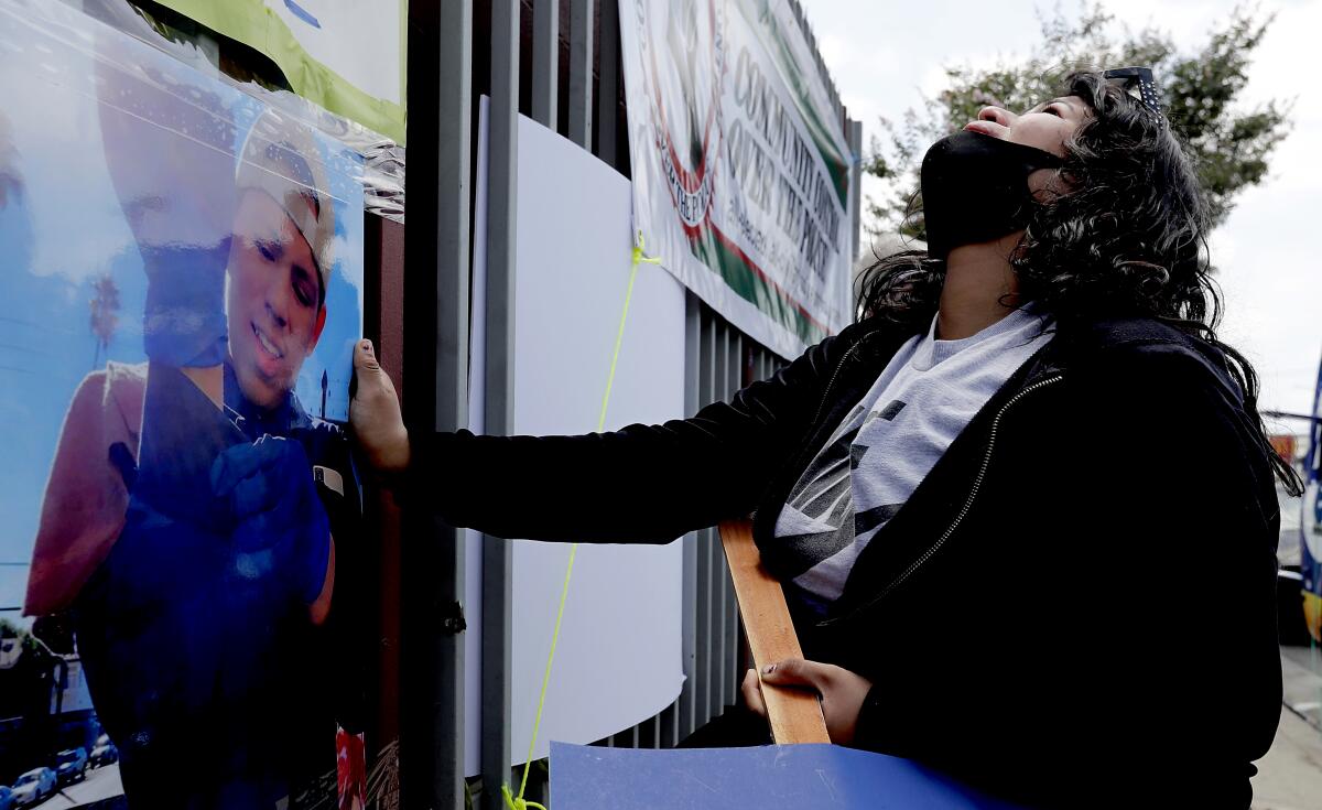 Jennifer Guardado looks to the sky and grieves as she touches a picture of her brother, Andres Guardado, at a memorial