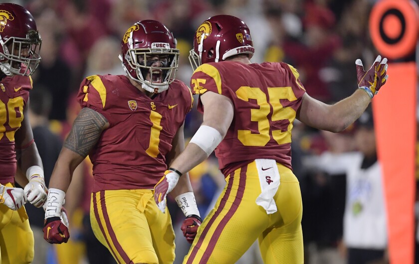 USC linebacker Palaie Gaoteote IV celebrates a sack with defensive lineman Christian Rector and linebacker Cameron Smith.