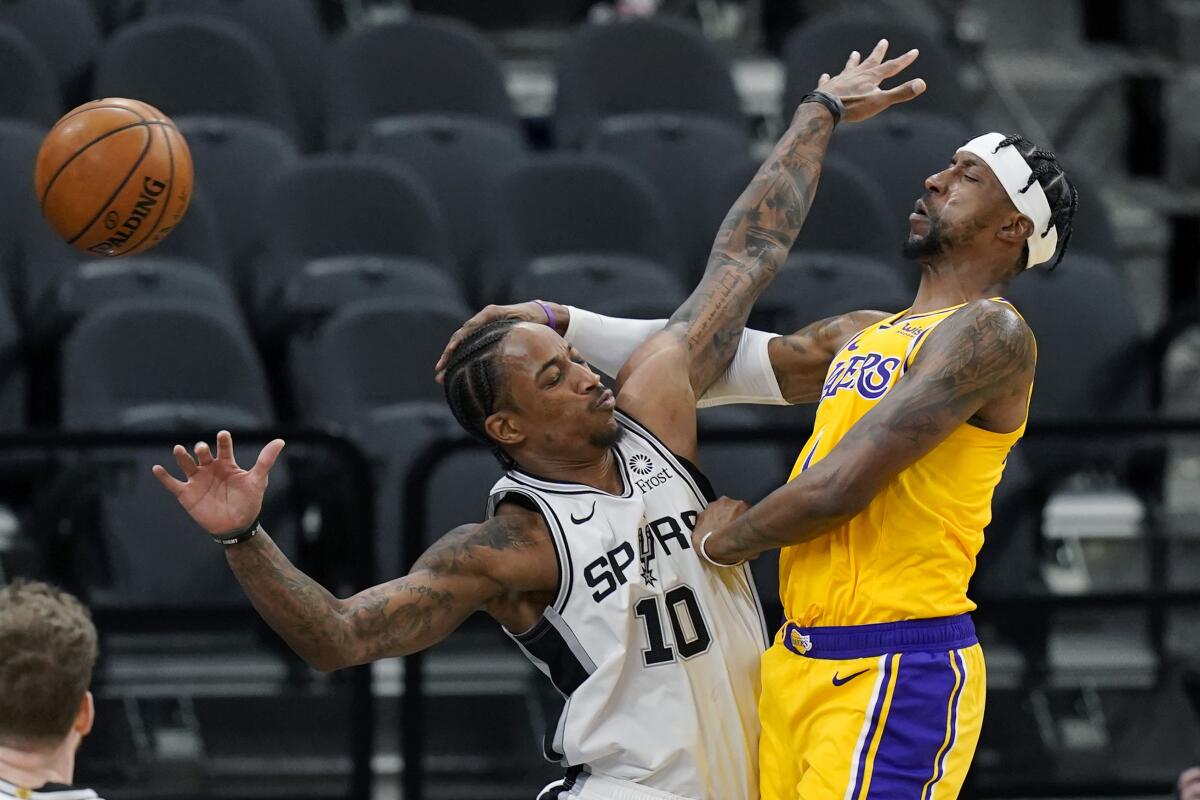 Lakers guard Kentavious Caldwell-Pope passes the ball around Spurs guard DeMar DeRozan on Dec. 30, 2020.
