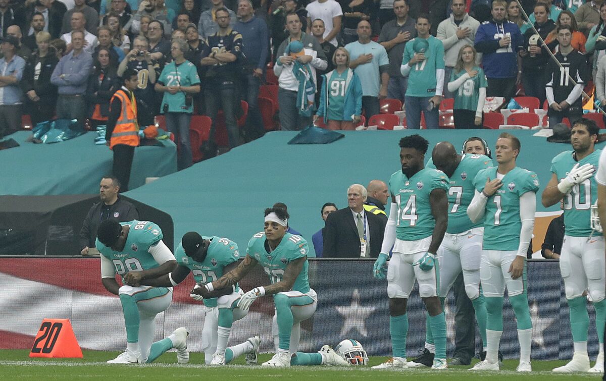 Miami Dolphins' Julius Thomas (89), Michael Thomas (31) and Kenny Stills take a knee as the national anthem is played before their game against the New Orleans Saints in London on Oct. 1.