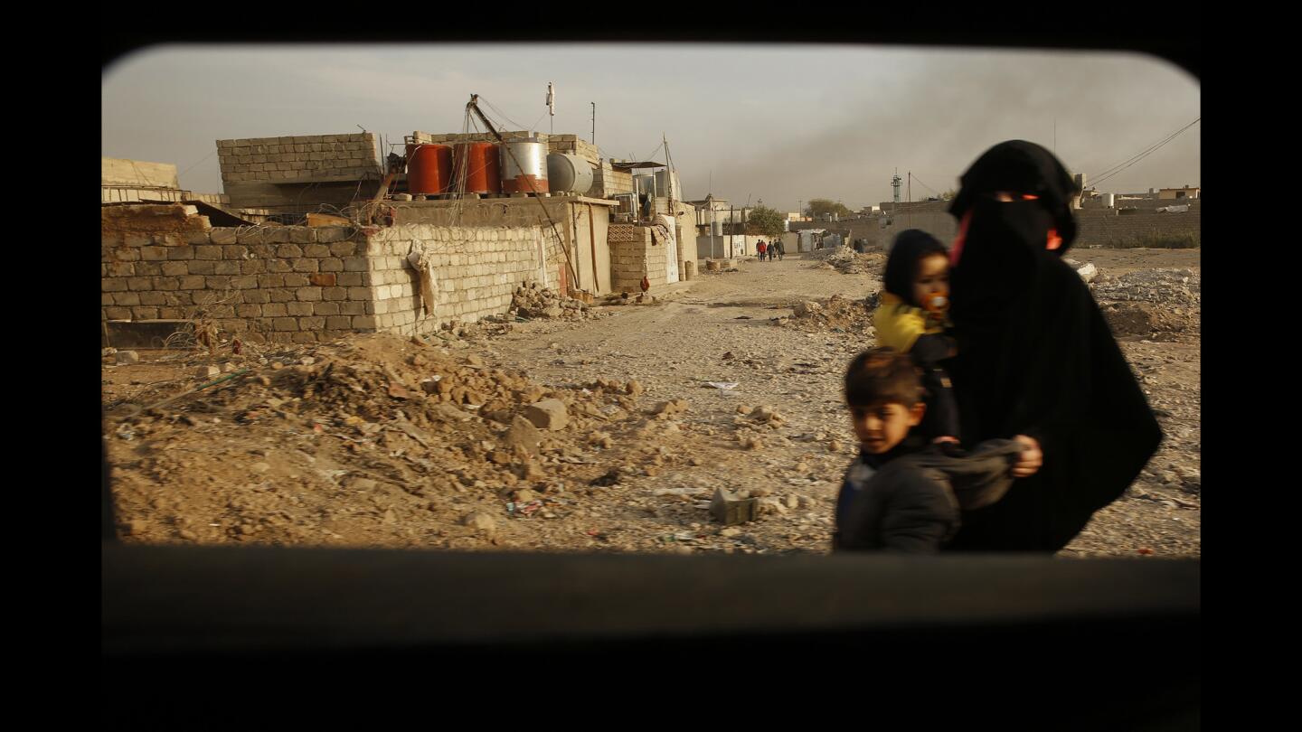 In the Cahra neighborhood of Mosul, a woman and her children walk in the streets despite the battle between Iraqi forces and Islamic State militants.