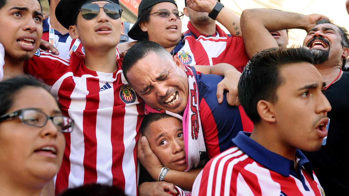 Chivas USA fan Juan Gutierrez, center, holds his son Angel, 11, while reacting immediately after the team's season finale Sunday against the San Jose Earthquakes at StubHub Center.