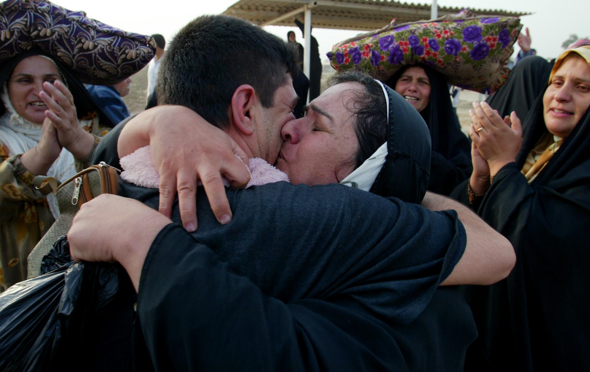 A man hugs his mother as other people around them clap