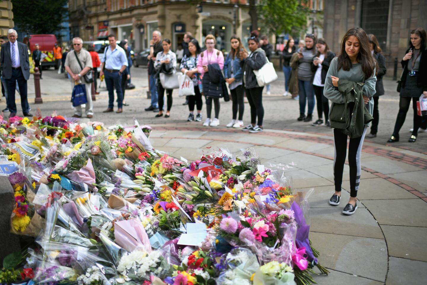 People pause to look at floral tributes and messages in St. Ann Square on May 24, 2017, in Manchester, England.