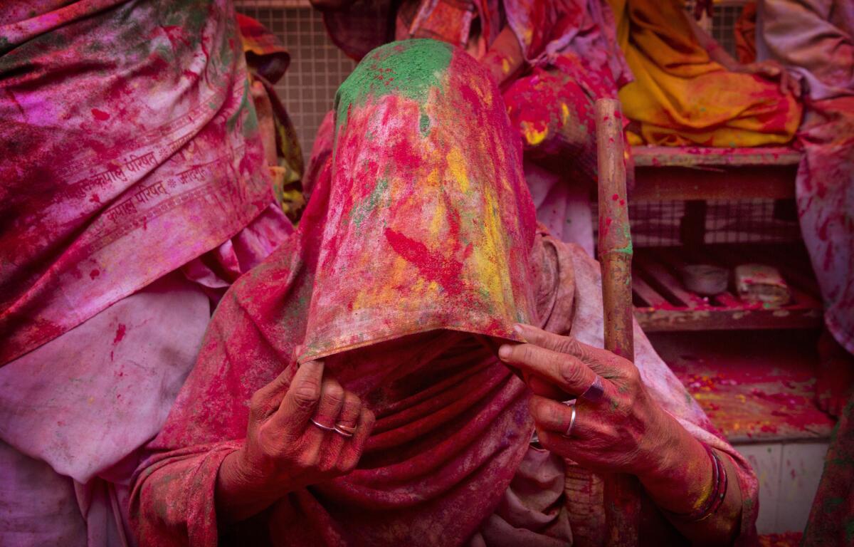 An Indian widow smeared with colors covers her face during Holi celebrations, the arrival of spring festival, at the Gopinath temple in Vrindavan, India.