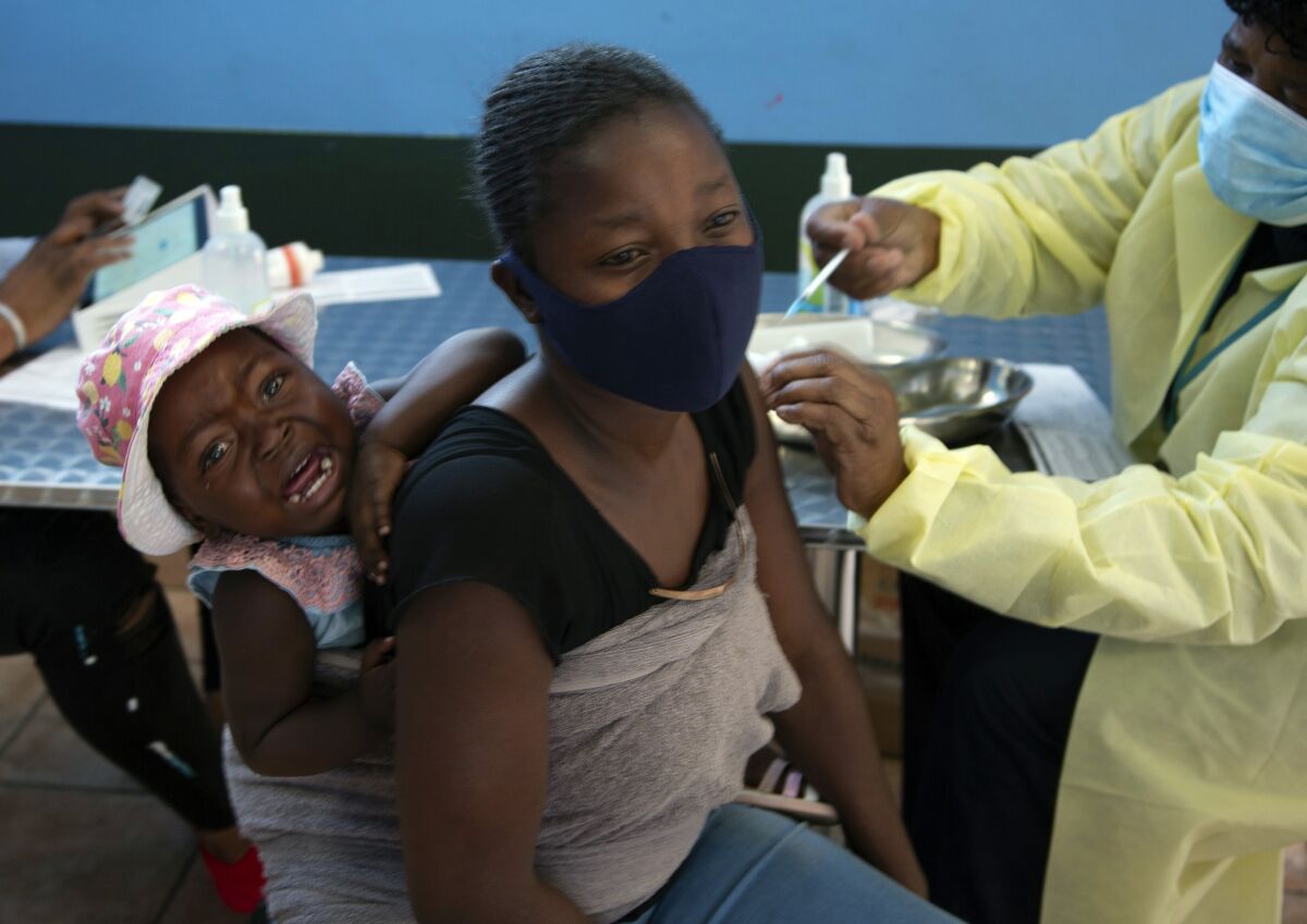 A baby cries as her mother receives her Pfizer vaccine against COVID-19. 