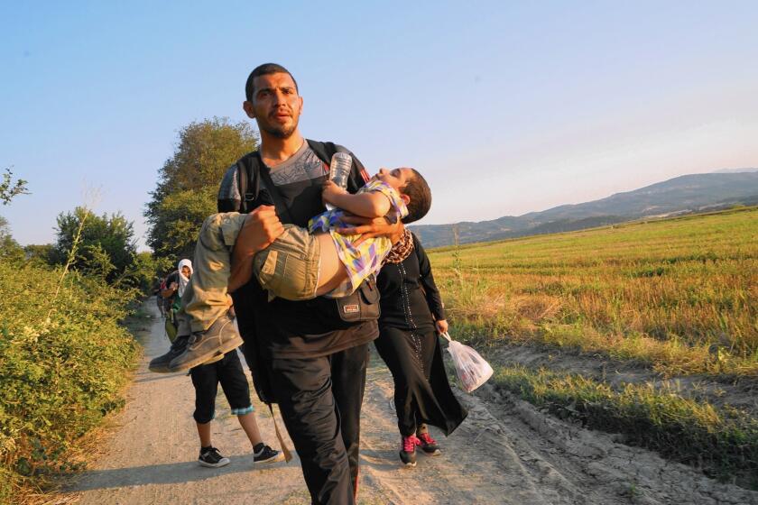 Mohammed Rantisi, a Syrian-born Palestinian, carries his son Adam toward the Macedonian border. Mohammed and his family are headed to Denmark, where his ailing mother lives.