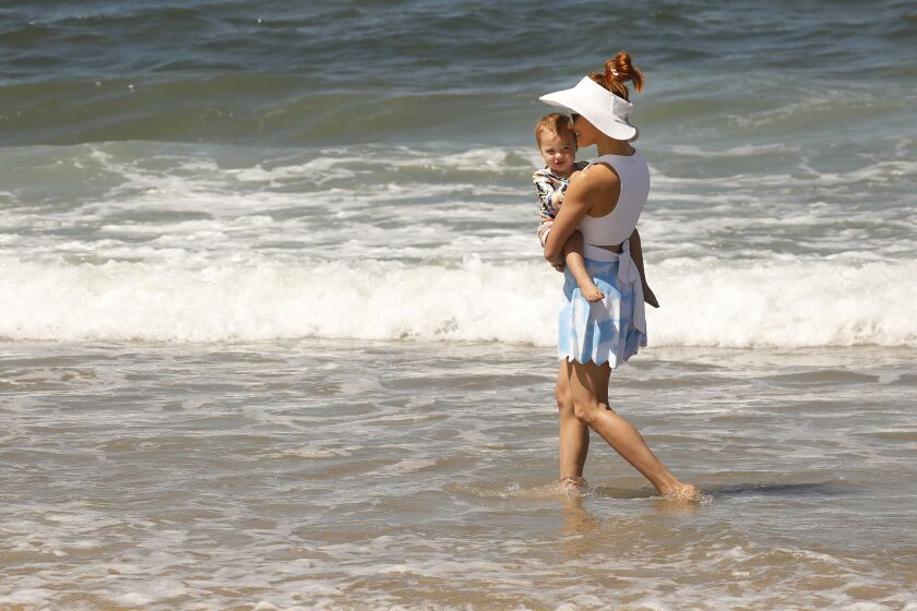LOS ANGELES, CA - JUNE 11: Amy Paffrath plays with nearly 2-year-old daughter Ember Seeley in the surf at Playa Del Rey Beach Friday morning. The family from Echo Park is spending time at the beach waiting for Mom to arrive at LAX. "We take any chance we can get to go to the beach. We can have a vacation any time we want because we live here," Amy said. People are heading to the beach as temps are starting to climb Friday morning and hot weather is headed to the Southwest corner of the Nation for the coming week. Play Del Rey on Friday, June 11, 2021 in Los Angeles, CA. (Al Seib / Los Angeles Times).