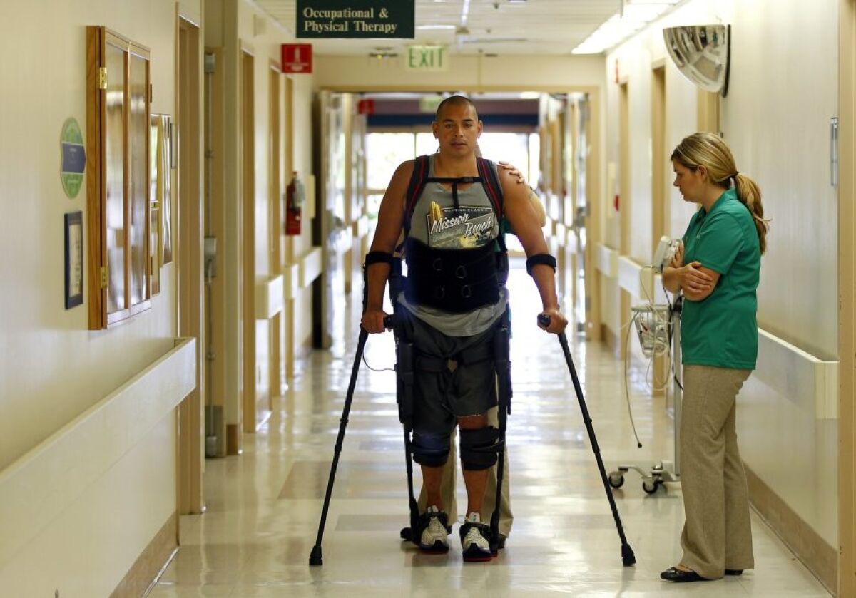 Hermes Castro walks with a help of an Ekso Bionics exoskeleton at Scripps Memorial Hospital Encinitas. Physical therapist Alyson Cavanaugh monitors Castro and the device. The exoskeleton is the first one in the county. Castro is a paraplegic patient who was hit by a vehicle while riding his bicycle.