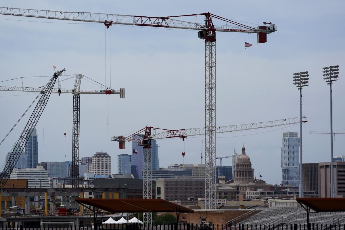Construction cranes hover over downtown and near Austin, Texas. 
