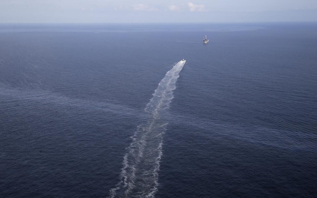 FILE - In this March 31, 2015, file aerial photo, the wake of a supply vessel heading towards a working platform crosses over an oil sheen drifting from the site of the former Taylor Energy oil rig in the Gulf of Mexico, off the coast of Louisiana. A federal appeals court says the owner of Gulf of Mexico oil wells broken in 2004 cannot demand damages from a federal contractor who says his equipment has captured enough oil to fill scores of tank trucks. The 5th U.S. Circuit Court of Appeals on Thursday, July 1, 2021, upheld a district court ruling that Taylor Energy Co. LLC cannot sue Couvillion Group LLC for trespass. (AP Photo/Gerald Herbert, File)