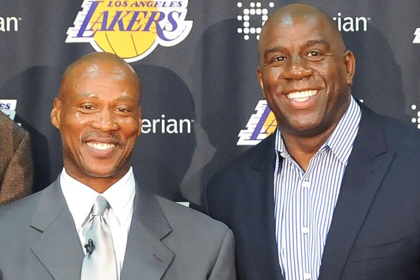 Lakers Coach Byron Scott, left, poses with former teammate Magic Johnson during a press conference at the team's training facility in El Segundo back in July.