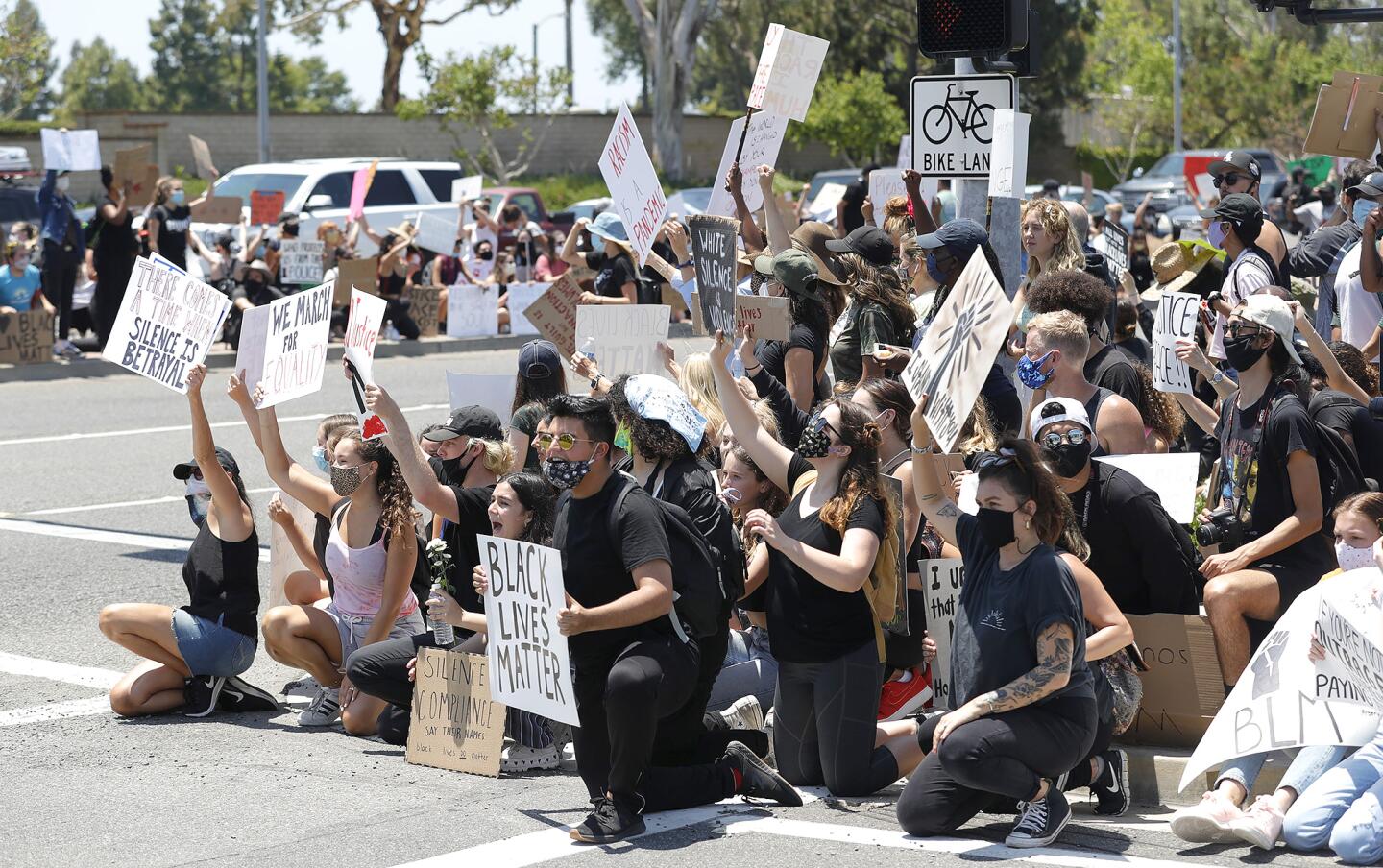 Protesters take a knee at the entrance to Fashion Island during a Black Lives Matter protest which began at MacArthur Boulevard and East Coast Highway in Newport Beach on Wednesday.