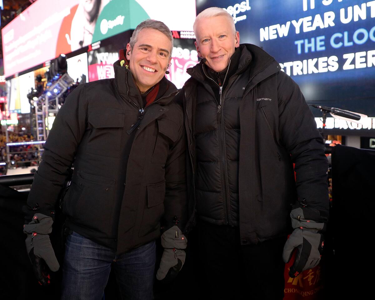 Two men smiling in winter coats and gloves in Times Square, New York