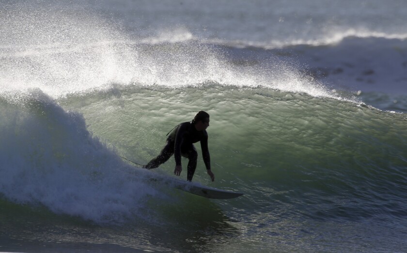 Surfers near the Huntington Beach Pier enjoy big, wind-blown waves on a warm summerlike day Feb. 5, 2016.