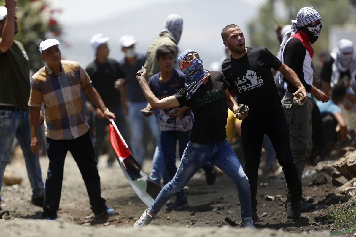 Palestinian demonstrators hurl stones at Israeli troops during a protest Israel's plan to annex parts Israel's plan to annex parts of the West Bank and Trump's mideast initiative, in the West Bank village of Kufr Qaddumm near Nablus, Friday, July 3, 2020.(AP Photo/Majdi Mohammed)