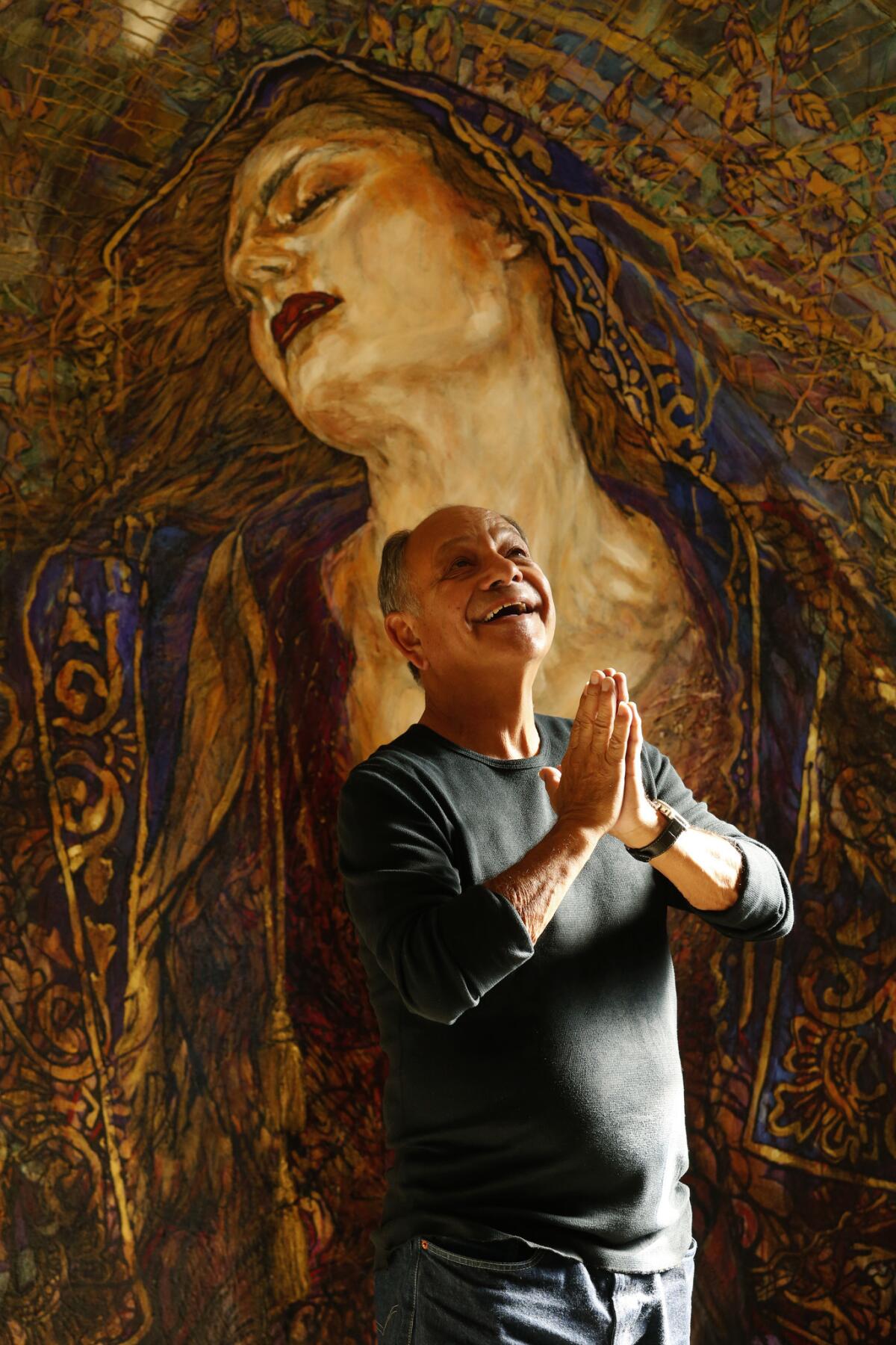 Cheech Marin strikes an angelic pose in front of a painting by Chicano artist George Yepes entitled, "Axis Bold As Love," in his Pacific Palisades home on March 27. (Genaro Molina / Los Angeles Times)