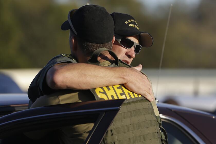 A pair of Placer County sheriff's deputies embrace after a suspect was arrested who allegedly shot and killed two deputes, wounded a third and a bystander during a series of shootings that spanned across two California counties.