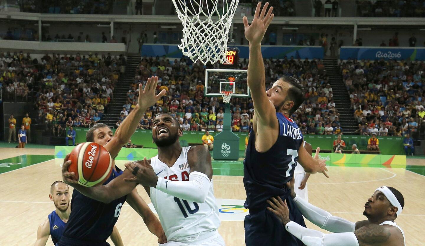 Kyrie Irving (USA) of the USA makes a layup as Antoine Diot (FRA) of France and Joffrey Lauvergne (FRA) of France defend.