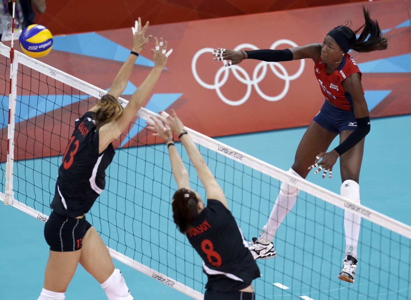 Team USA's Destinee Hooker, right, spikes the ball over Turkey's Neriman Ozsoy, left, and Bahar Toksoy during a women's preliminary volleyball match.